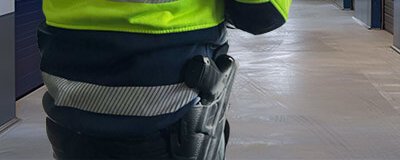 Sicherheitsmitarbeiter in Warnjacke mit Reflexstreifen und Holster in einem Gebäudeflur