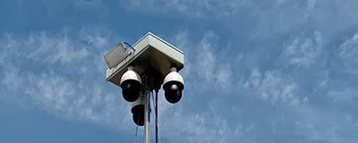 Mehrere Überwachungskameras an einem Mast vor blauem Himmel