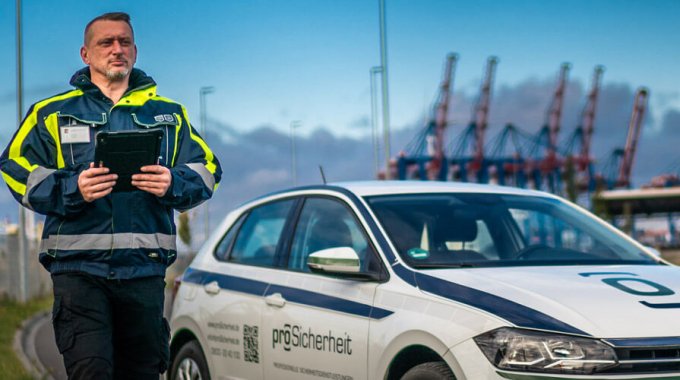 Mitarbeiter der Sicherheitsbranche neben Einsatzfahrzeug