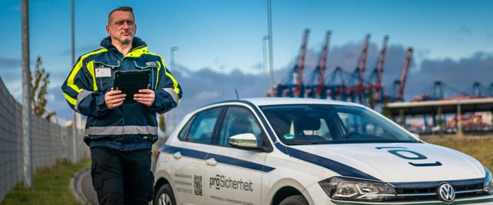 Mitarbeiter der Sicherheitsbranche neben Einsatzfahrzeug