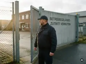 Sicherheitsmitarbeiter in dunkler Uniform bewacht das geschlossene Eingangstor eines Industriegeländes in Norddeutschland.